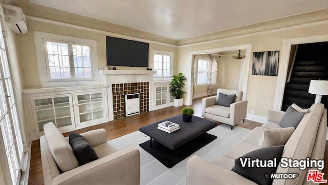 living room featuring a healthy amount of sunlight, wood-type flooring, a notable chandelier, and a wall mounted air conditioner