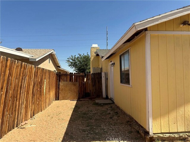 10907 Bartlett, Adelanto, CA 92301 - view of home's exterior featuring roof with shingles and a gate