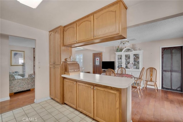 kitchen featuring ceiling fan, kitchen peninsula, light hardwood / wood-style floors, and light brown cabinets