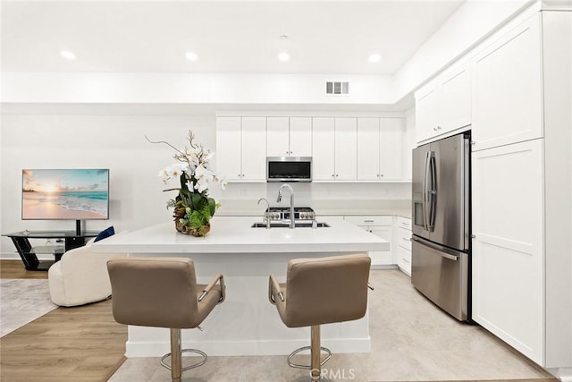 kitchen featuring a kitchen island with sink, appliances with stainless steel finishes, and white cabinetry