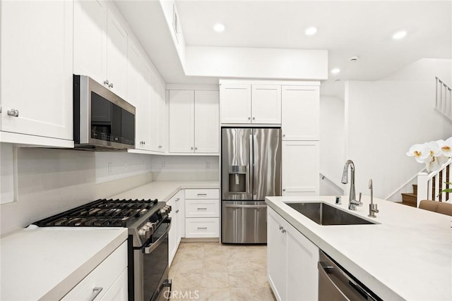 kitchen with light tile patterned floors, appliances with stainless steel finishes, white cabinetry, and sink