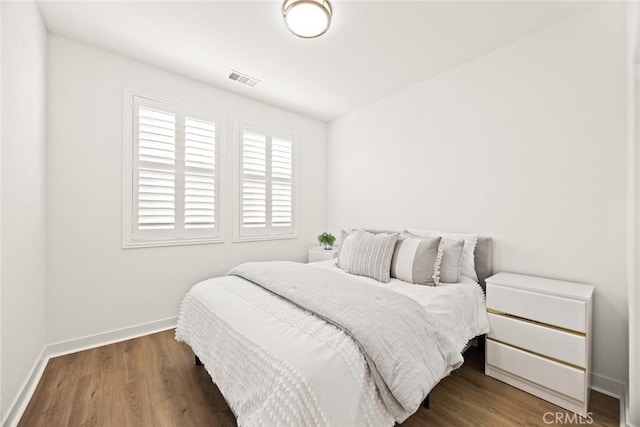 bedroom with visible vents, wood finished floors, and baseboards