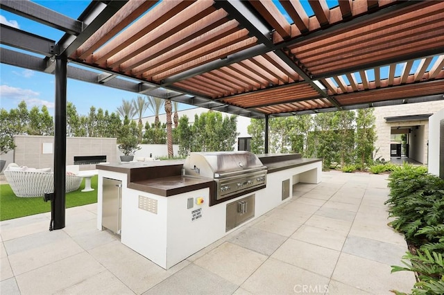 view of patio with fence, area for grilling, exterior kitchen, and a pergola