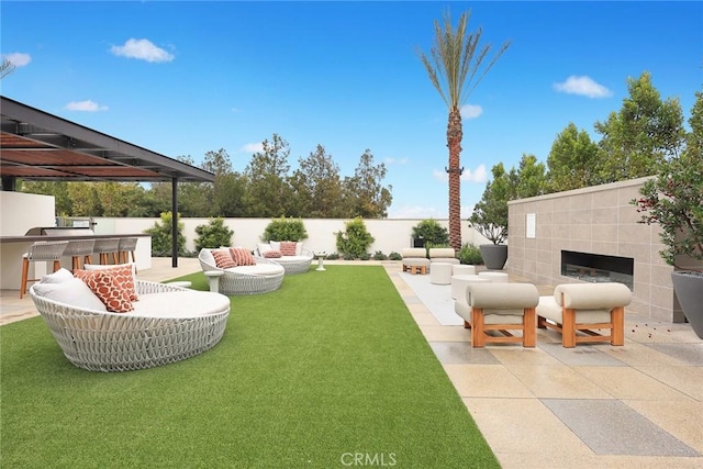 view of yard featuring an outdoor living space with a fireplace, a patio, a fenced backyard, and area for grilling