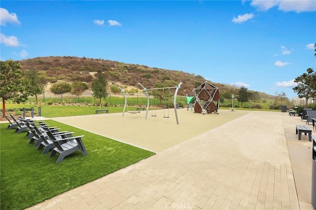 community jungle gym with a mountain view and a yard