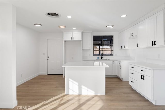 kitchen featuring sink, white cabinetry, light hardwood / wood-style flooring, and a kitchen island