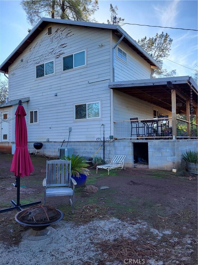 back of house with central AC and a fire pit