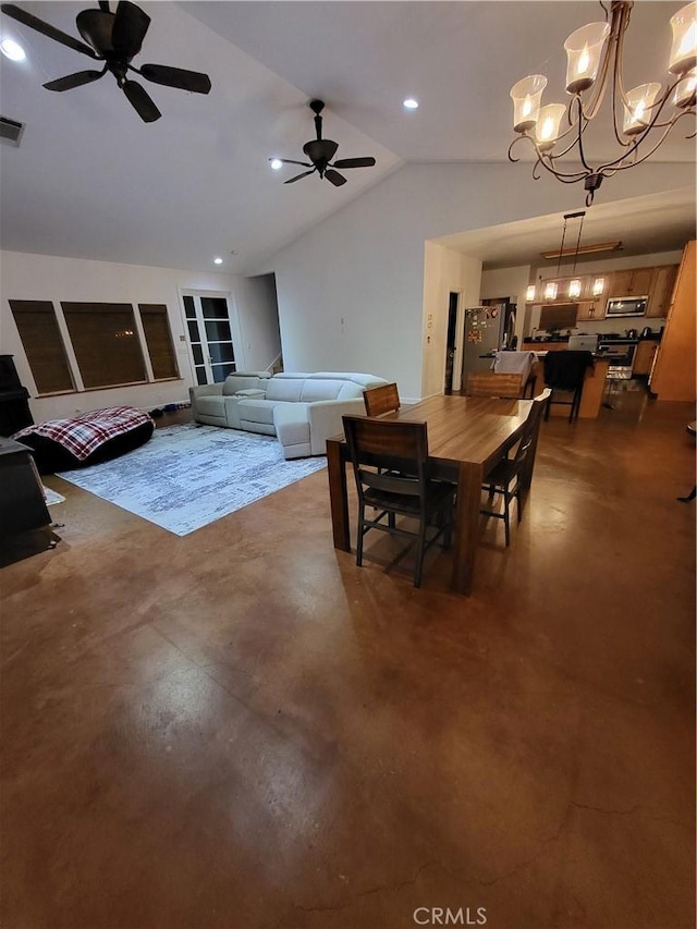 dining area featuring lofted ceiling, ceiling fan with notable chandelier, and concrete floors