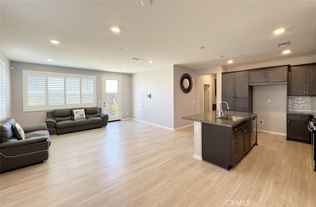 kitchen featuring sink, dark brown cabinetry, light hardwood / wood-style flooring, and a kitchen island with sink