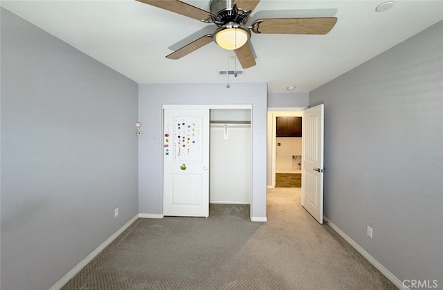 unfurnished bedroom featuring ceiling fan, light colored carpet, and a closet