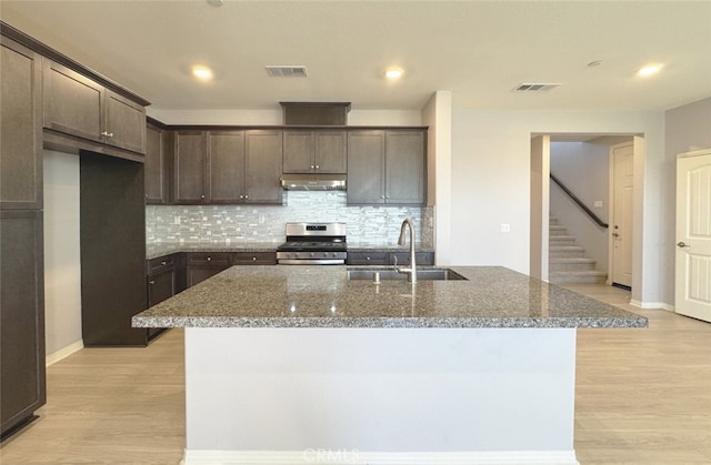 kitchen featuring stainless steel range, a kitchen island with sink, dark brown cabinetry, and sink