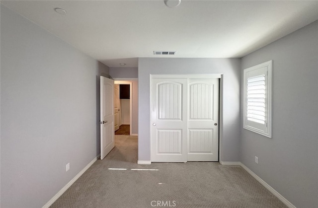 unfurnished bedroom featuring light carpet and a closet