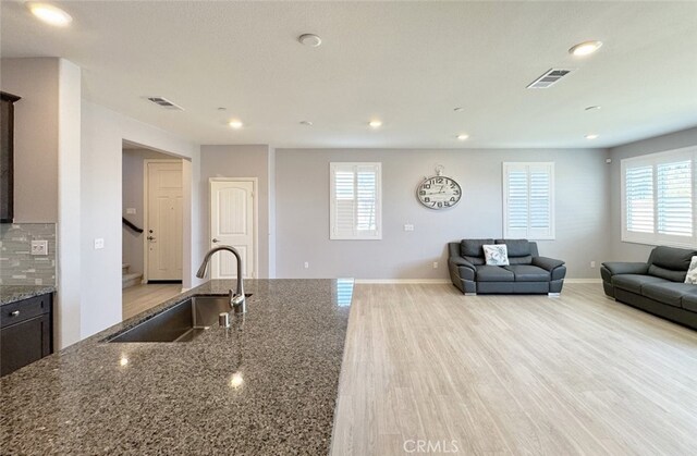 kitchen featuring decorative backsplash, sink, plenty of natural light, and stone counters