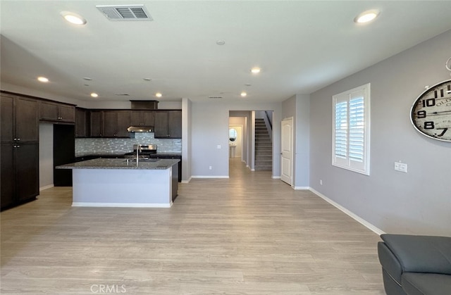 kitchen with dark brown cabinets, light hardwood / wood-style flooring, a center island with sink, and sink