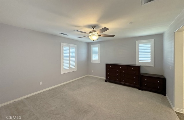 unfurnished bedroom with ceiling fan, light colored carpet, and multiple windows