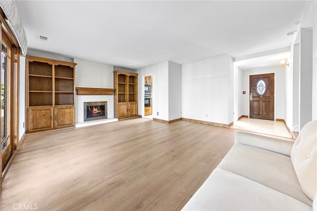 unfurnished living room with a large fireplace and light hardwood / wood-style flooring