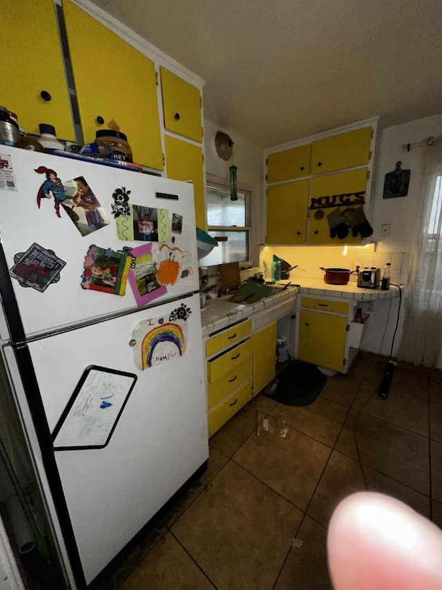 kitchen with white refrigerator, tile countertops, and dark tile patterned floors