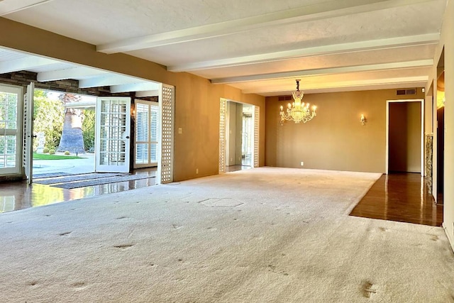 carpeted empty room featuring beam ceiling and an inviting chandelier