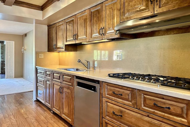 kitchen with appliances with stainless steel finishes, sink, backsplash, ornamental molding, and light wood-type flooring