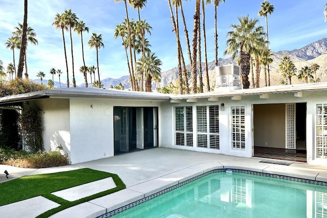 rear view of house with central AC, a mountain view, and a patio