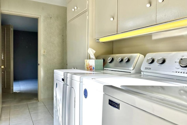 laundry room with light tile patterned floors, washing machine and clothes dryer, and cabinets