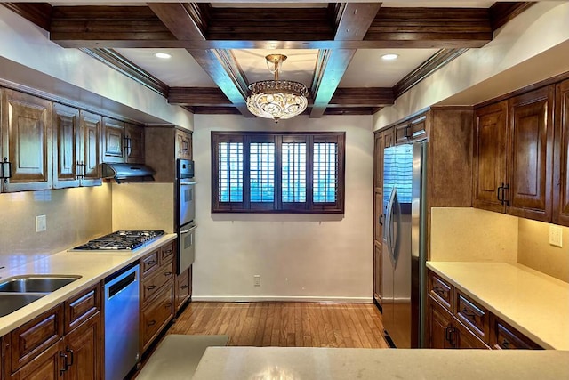 kitchen with a notable chandelier, light hardwood / wood-style floors, coffered ceiling, hanging light fixtures, and stainless steel appliances