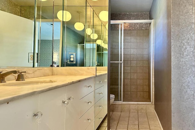 bathroom featuring a shower with shower door, toilet, vanity, and tile patterned flooring