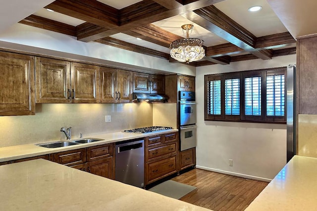 kitchen with ventilation hood, stainless steel appliances, a notable chandelier, decorative light fixtures, and sink