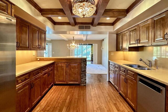 kitchen with appliances with stainless steel finishes, an inviting chandelier, sink, hanging light fixtures, and kitchen peninsula