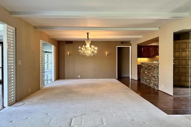 carpeted spare room with beamed ceiling and a chandelier