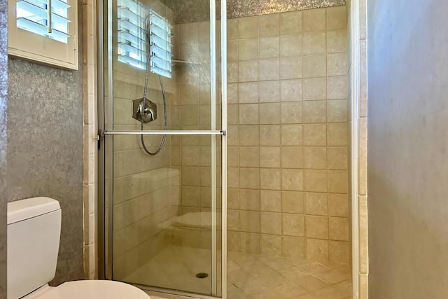 bathroom featuring toilet and a shower with door