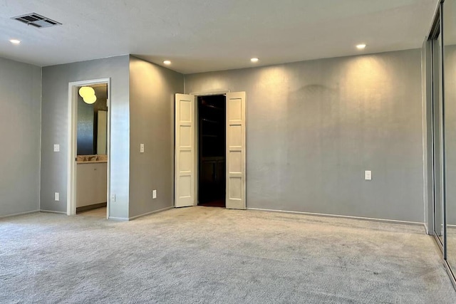 interior space with ensuite bathroom and light colored carpet