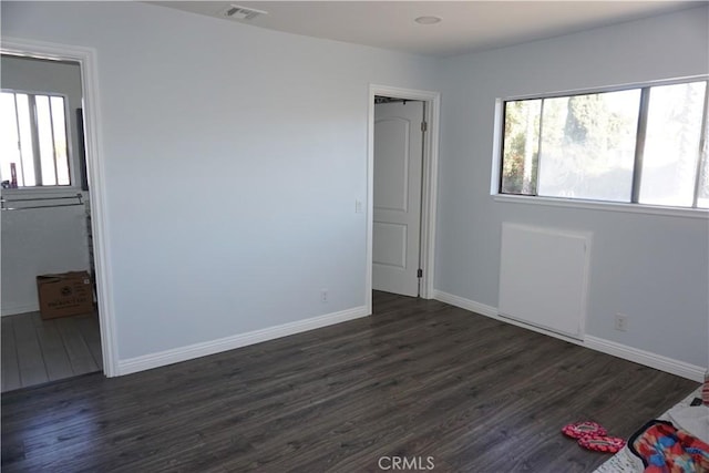 unfurnished bedroom featuring dark hardwood / wood-style floors and multiple windows