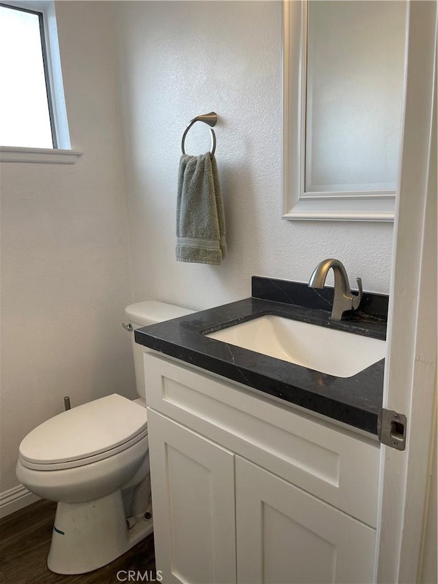 bathroom featuring toilet, wood finished floors, and vanity