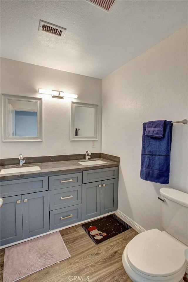 full bath featuring a sink, visible vents, toilet, and wood finished floors