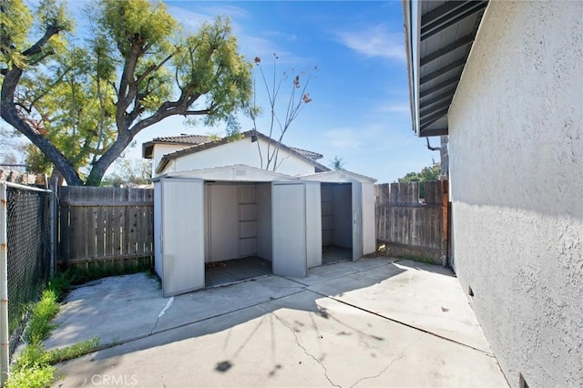 view of patio featuring an outbuilding, a storage unit, and a fenced backyard