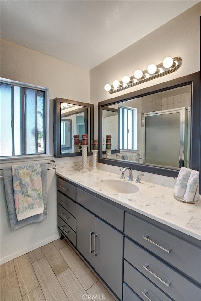 bathroom featuring wood tiled floor, vanity, and a shower stall