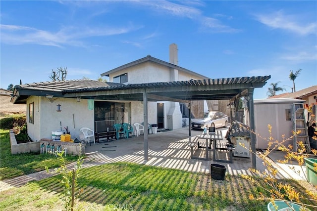 rear view of property featuring stucco siding, a lawn, and a patio area