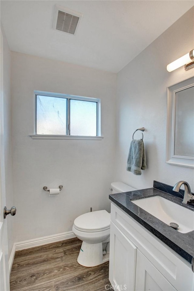 half bathroom featuring a wealth of natural light, visible vents, toilet, and wood finished floors