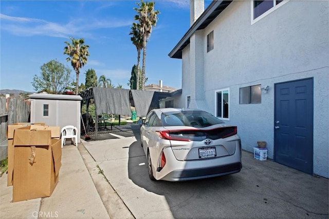 view of property exterior with fence, a chimney, and stucco siding