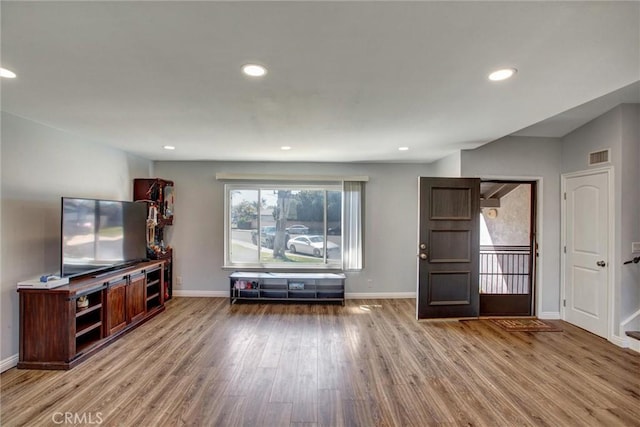 unfurnished living room with wood finished floors, visible vents, and baseboards