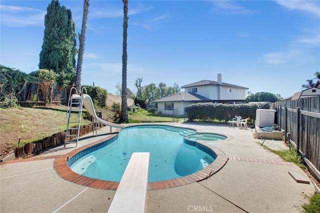 view of pool with a water slide, a fenced backyard, a diving board, a pool with connected hot tub, and a patio area