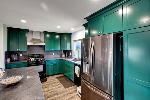 kitchen featuring black gas range oven, green cabinets, stainless steel refrigerator with ice dispenser, wall chimney exhaust hood, and a sink