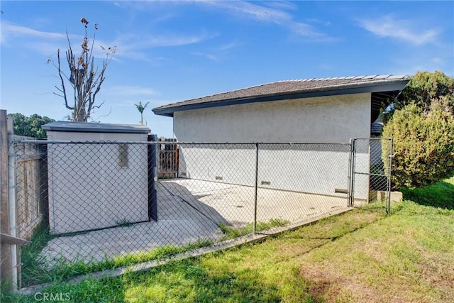 view of home's exterior featuring a gate, stucco siding, an outdoor structure, and fence