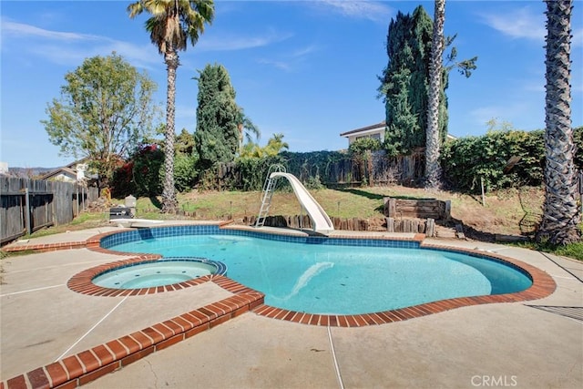 view of swimming pool featuring a pool with connected hot tub, a water slide, a fenced backyard, a patio area, and a diving board