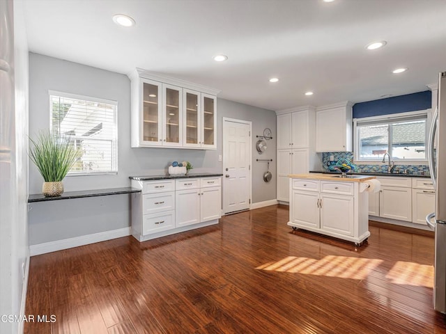 kitchen featuring dark wood-type flooring, decorative backsplash, white cabinets, and sink