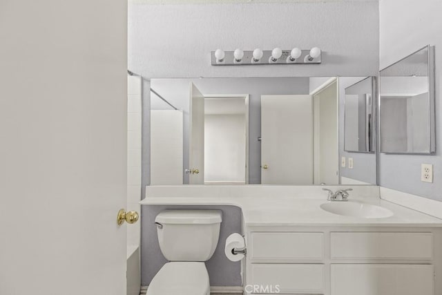 bathroom featuring walk in shower, vanity, and toilet