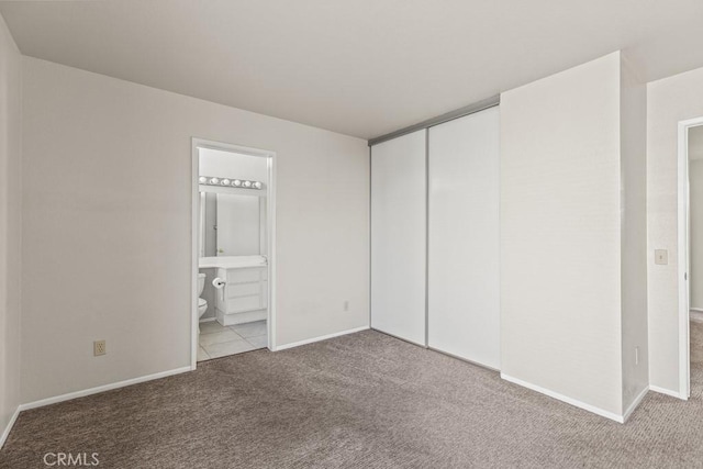 unfurnished bedroom with light colored carpet, connected bathroom, and a closet