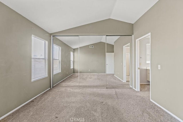 unfurnished bedroom with vaulted ceiling, light colored carpet, and a closet