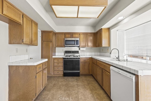 kitchen with sink, white appliances, tile countertops, and light tile patterned floors